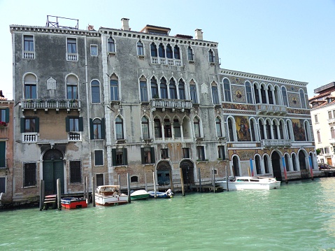 Venice, Veneto, Italy - June 2, 2014: The Palazzo Da Mula Morosini built in Gothic style in the fifteenth century. On the right the Palazzo Barbarigo, built in the sixteenth century in the High Renaissance, has a facade of the most characteristic of the Grand Canal adorned with Murano glass frescoes and mosaics. It is currently the headquarters of glassmaking company Pauly & C.-Compagnia Venezia Murano