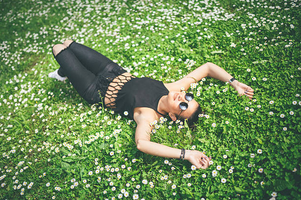 young hipster woman lying on a meadow in the park