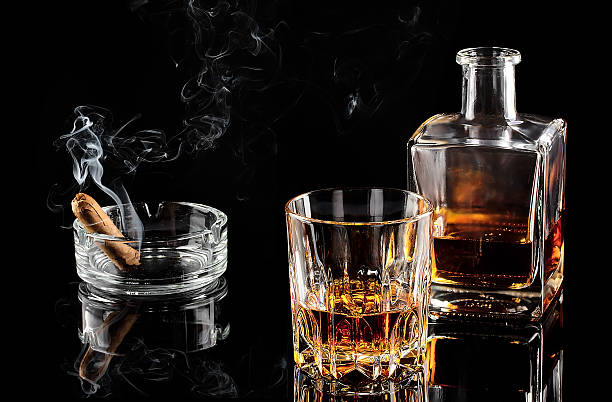 Glass of whiskey and a carafe of steaming cigar stock photo