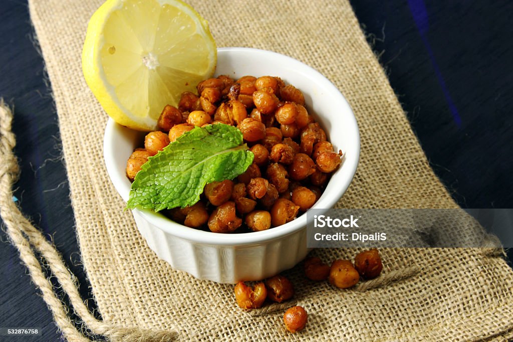 Roasted Chickpeas in a bowl Roasted Chickpeas with cumin, salt,  red chilli powder and lemon in a bowl on a wooden background with copy space Appetizer Stock Photo
