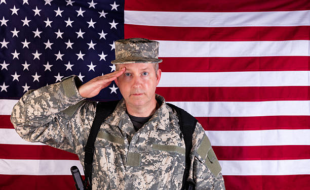 istock Male veteran solider saluting with USA flag in background while 532879506
