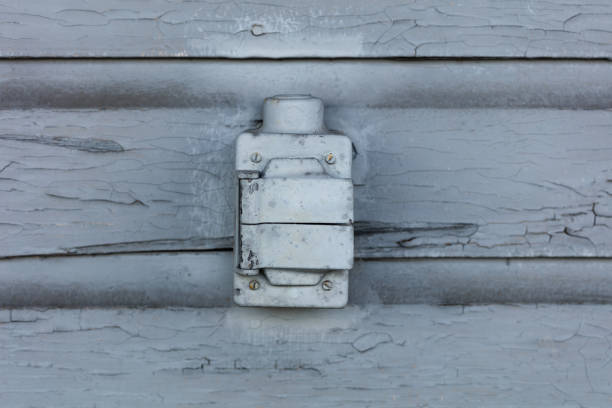 Old electric outlet box with cracking and peeling lead paint off of wood sliding.