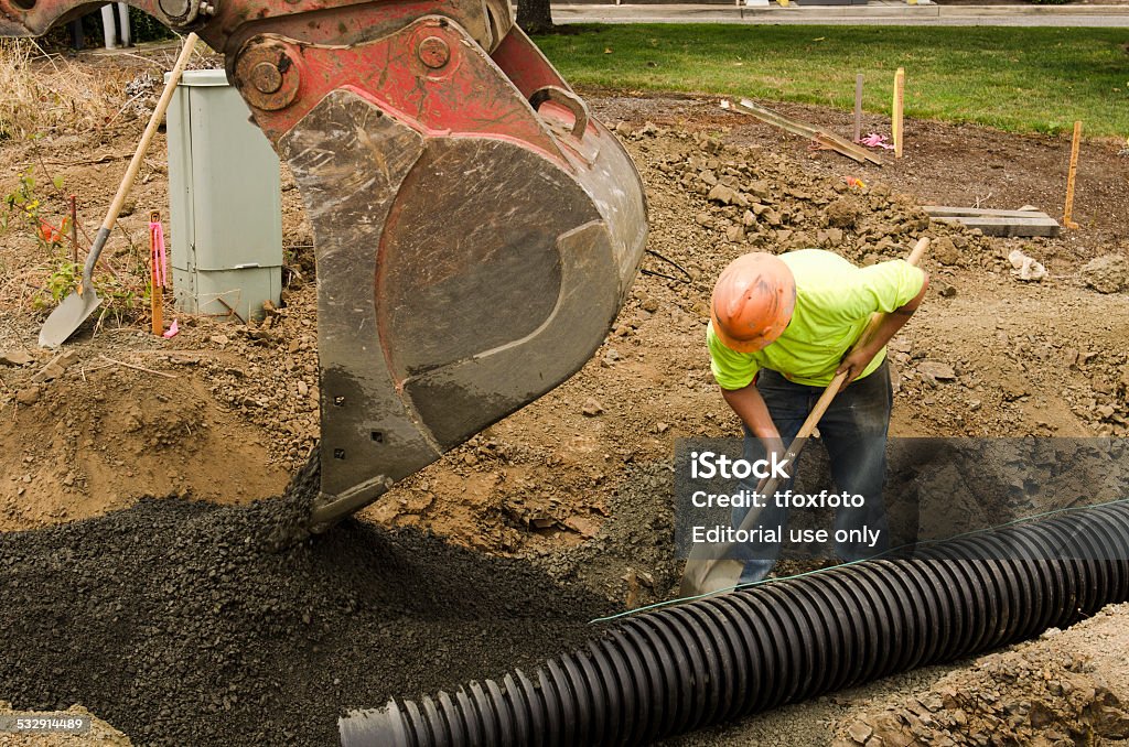 Domestic Sewer Roseburg, OR, USA - July 22, 2014: Excavation construction contractor installing a domestic black plastic sewer drain on a new commercial street filling with gravel Plastic Stock Photo