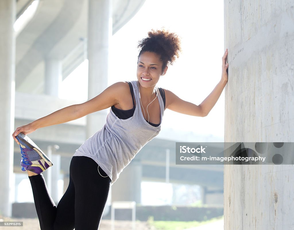 Happy young fitness woman stretching outdoors Portrait of a happy young fitness woman stretching outdoors 20-29 Years Stock Photo