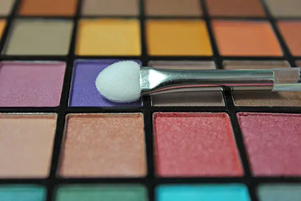 Close up colorful eyeshadow palette. Focus on the make up applicator.