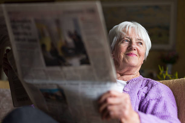 senior mujer leyendo periódico de la mañana - mujer leyendo periodico fotografías e imágenes de stock