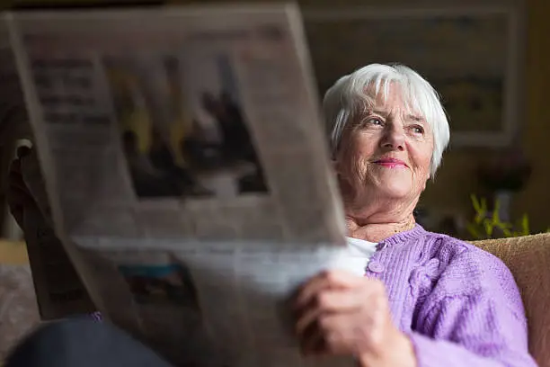 Photo of Senior woman reading morning newspaper