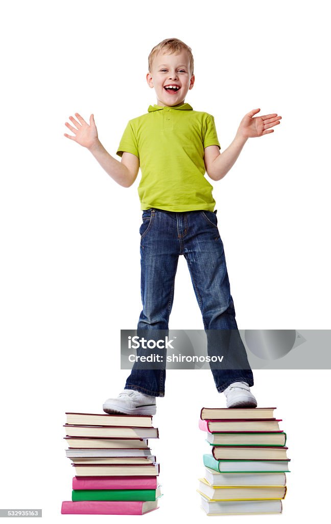 Curious boy A cheerful boy standing on two heaps of books 2015 Stock Photo