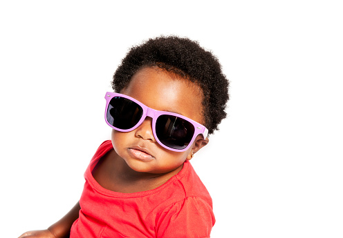 Cute studio photograph of a baby wearing purple sunglasses