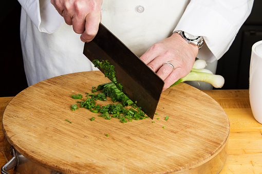 Using Chinese cleaver to slice scallions on Asian style cutting board