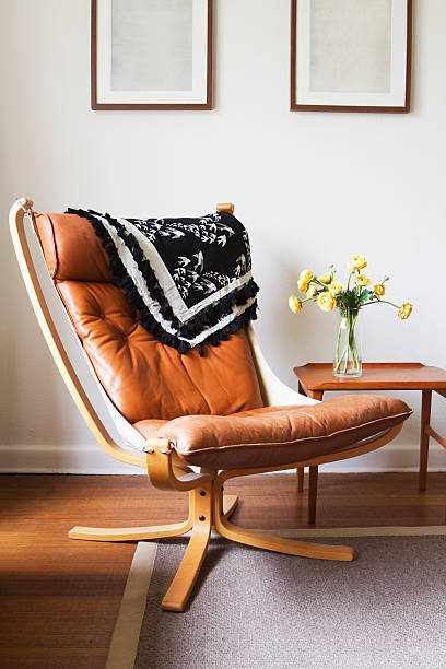 Vintage retro tan leather danish chair and table Vintage retro tan leather danish chair and table with vase of flowers leather cushion stock pictures, royalty-free photos & images