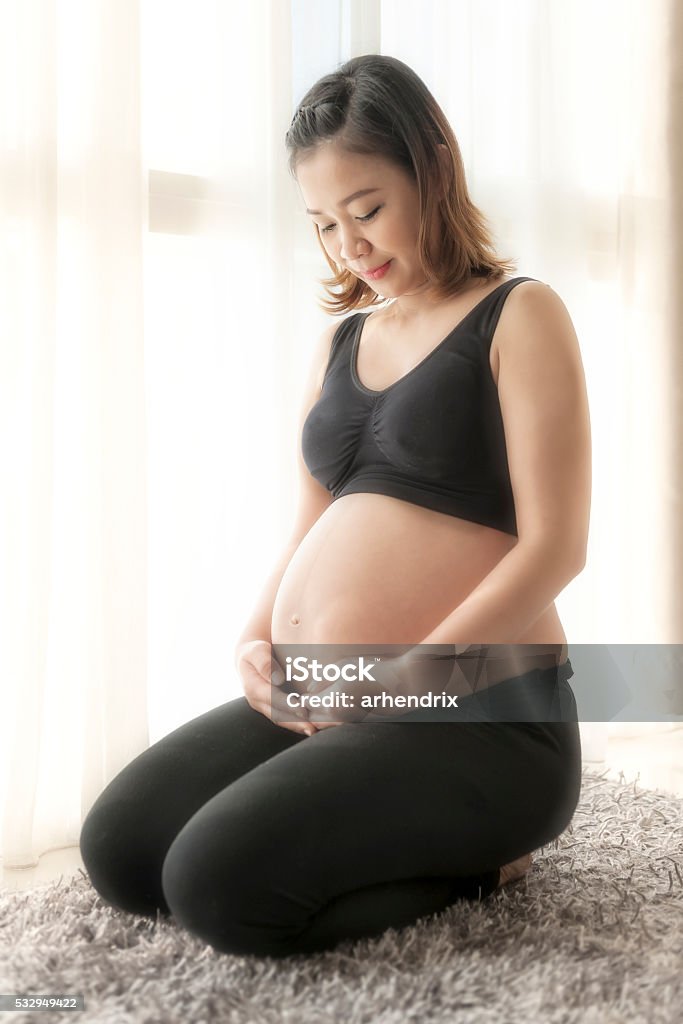 Asian girl is going to be a mom Beautiful pregnant asian young woman touching her belly and smiling Adult Stock Photo