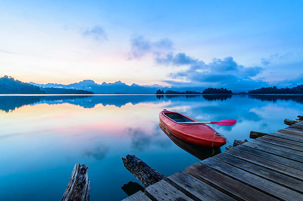 istock Canoe floating on the calm water under amazing sunrise 532949828