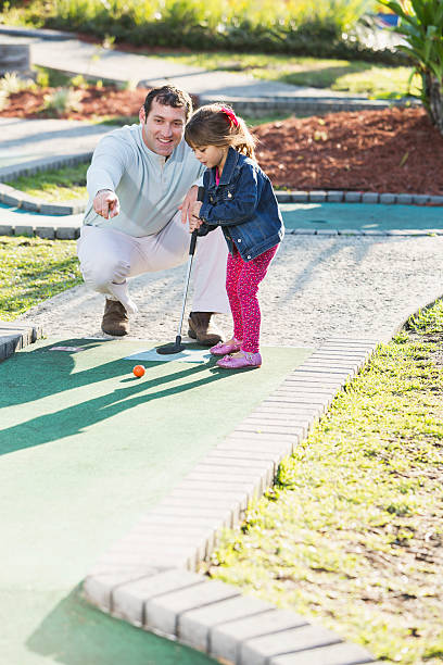 istock Little girl with father playing miniature golf 532953601