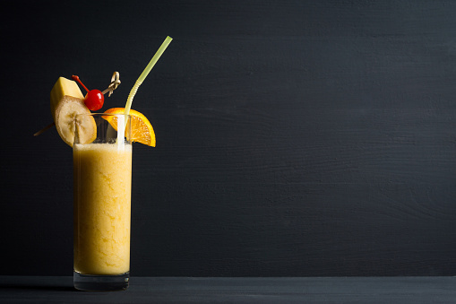 Banana cocktail with fruit decoration on the wooden background