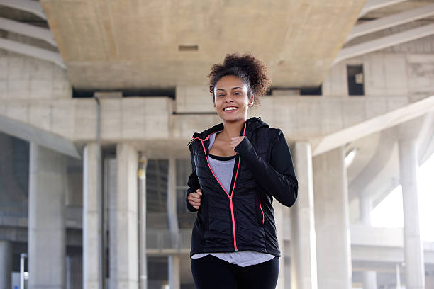 istock Smiling young woman jogging in urban environment 532960593