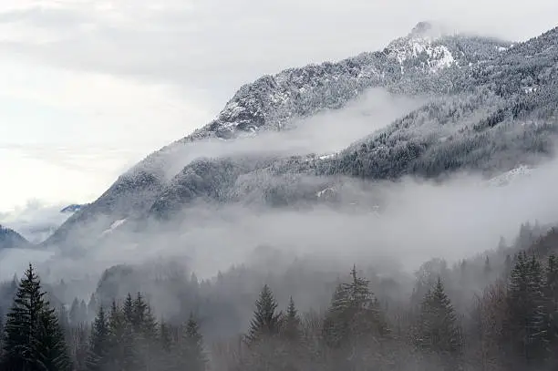 Mountain valley with snow and low clouds.