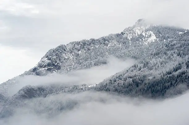 Mountain valley with snow and low clouds.