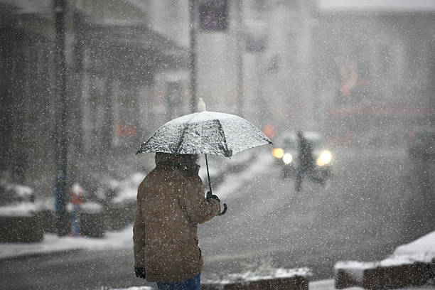 mann mit regenschirm im schnee sturm - schneien stock-fotos und bilder