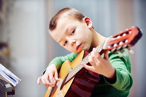 Little boy is playing the guitar at home 