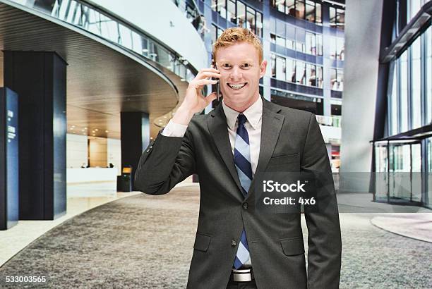 Cheerful Businessman On Mobile In The Office Stock Photo - Download Image Now - 2015, 25-29 Years, Adult