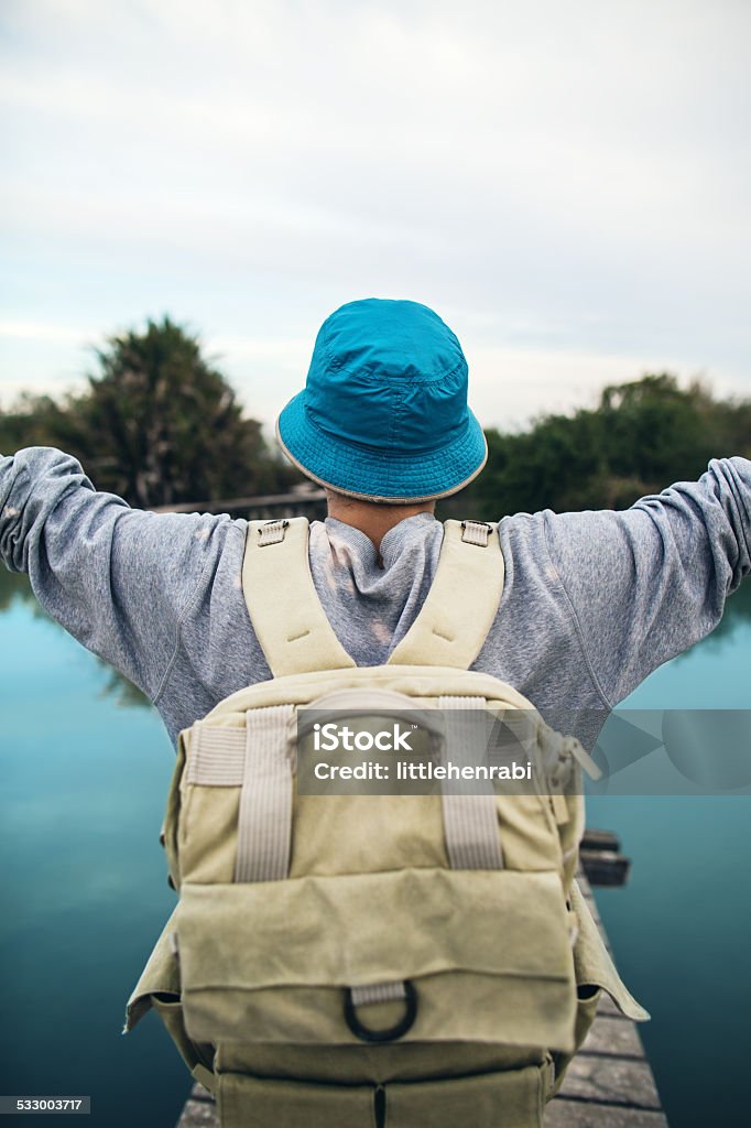 traveler on the blue lake tourist man with outstretched arms standing on the wooden bridge over glossy blue lake 2015 Stock Photo