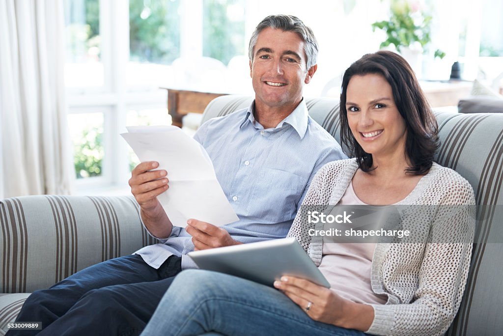 Our home finances are looking good Shot of a couple paying their bills online with their digital tablet 2015 Stock Photo