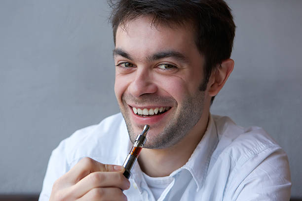 istock Cool young man holding electric cigarette indoors 533010365