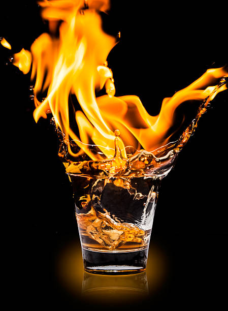 istock Glass with whiskey splash and fire on black background 533031123