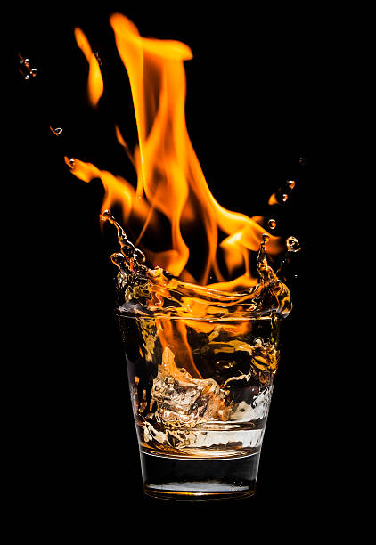 istock Glass with whiskey splash and fire on black background 533031219