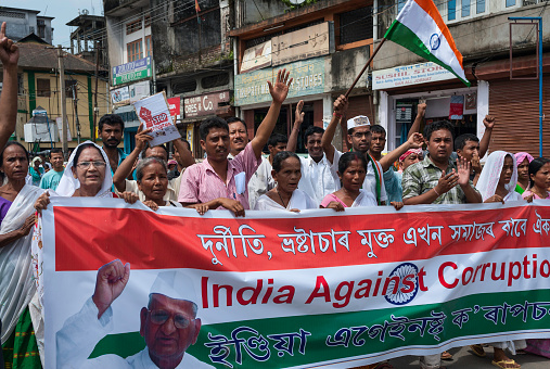 Jorhat, India - August 23, 2011: Demonstrators against corruption wave banner and Indian national flag against corruption in India on August 23, 2011 in Jorhat, Assam, India. An image of Anna Hazare, a popular polician, in on the banner. 