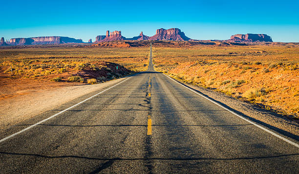 monument valley diritto strada del deserto occidentale con inconfondibile panorama utah - monument valley usa panoramic foto e immagini stock