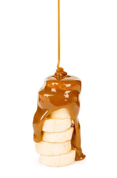 caramel est versée sur une banane. - caramel sauces sweet sauce pouring photos et images de collection