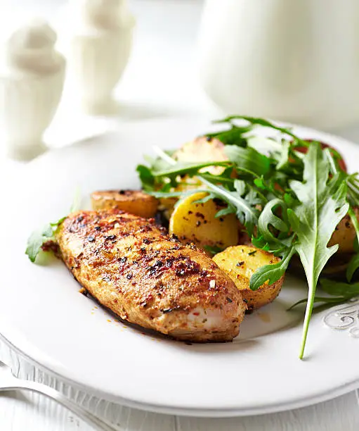 Spiced chicken breast with baked potatoes and arugula 