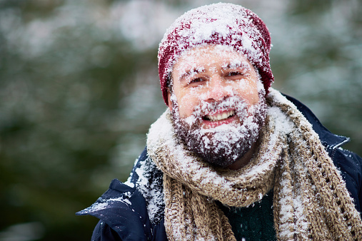 Portrait of happy bearded man covered with snow