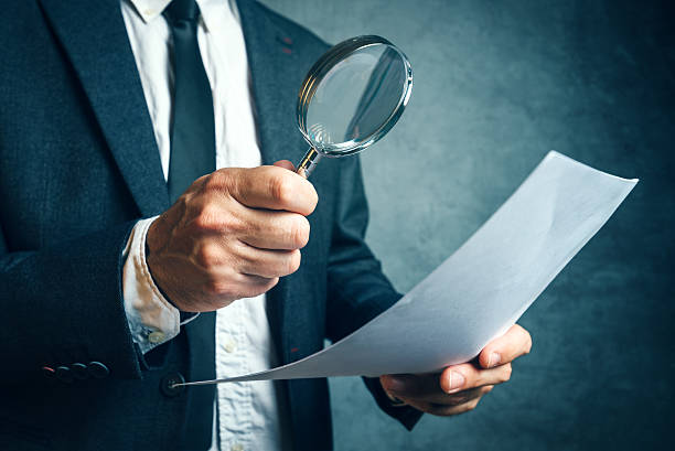 Tax inspector investigating financial documents through magnifyi stock photo