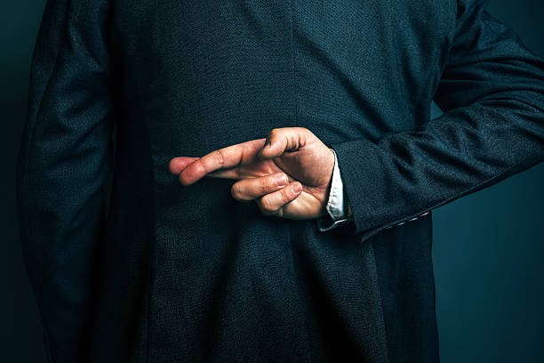 Lying businessman holding fingers crossed behind his back Dishonest businessman telling lies, lying businessperson holding fingers crossed behind his back hypocrisy stock pictures, royalty-free photos & images