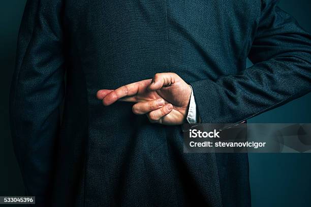 Lying Businessman Holding Fingers Crossed Behind His Back Stock Photo - Download Image Now