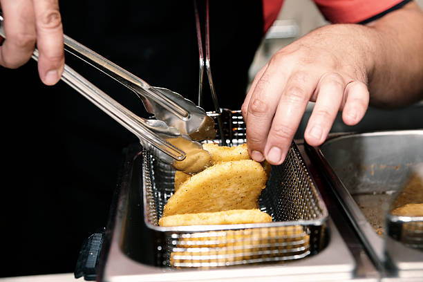 cozinheiro chefe cozinhar nuggets é uma profunda fritadeira, em tons - commercial kitchen restaurant retail stainless steel imagens e fotografias de stock