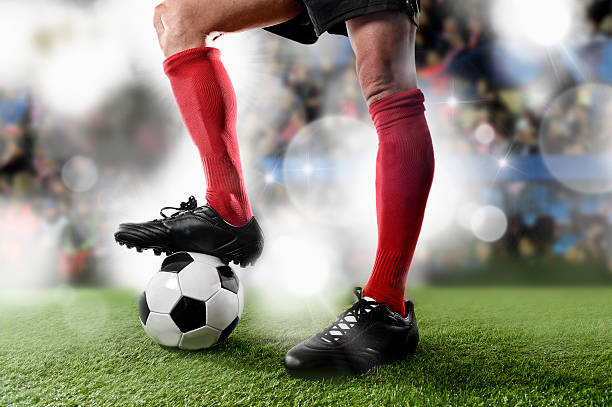 футбольный игрок в красный носки играя с мячом на стадион - human muscle flash стоковые фото и изображения