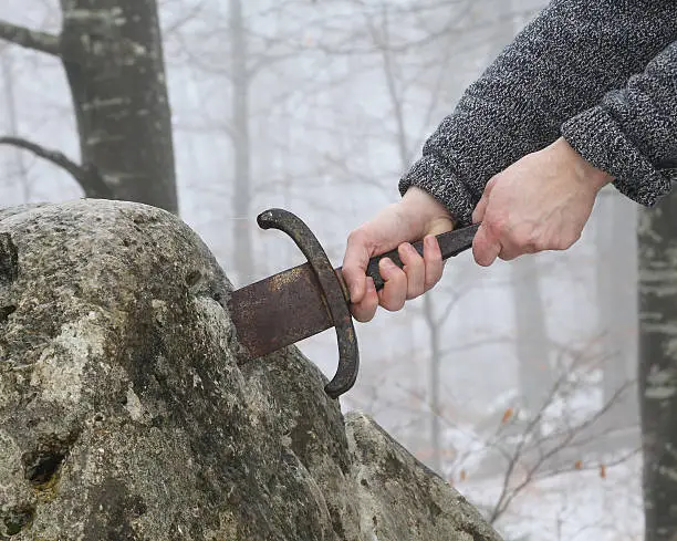 Hand of the valiant knight tries to remove the magical Excalibur sword in the stone