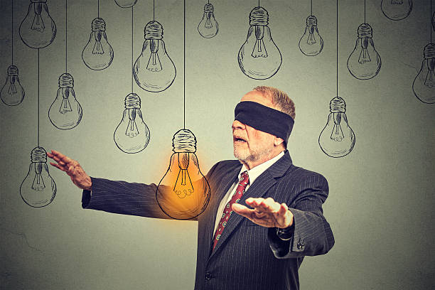 istock Blindfolded senior man walking through light bulbs searching for idea 533050800