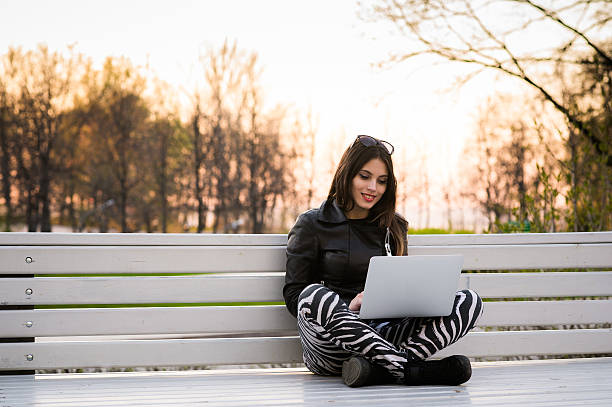 Close portrait of gorgeous dark-hair woman student using laptop Portrait of beautiful smiling dark-haired young woman, against summer green park. desiderius erasmus stock pictures, royalty-free photos & images