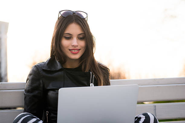 Close portrait of gorgeous dark-hair woman student using laptop Portrait of beautiful smiling dark-haired young woman, against summer green park. desiderius erasmus stock pictures, royalty-free photos & images