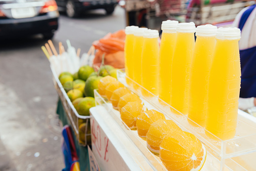 This is horizontal, color photograph of freshly squeezed citrus juice for sale along the sidewalk of Yaowarat Road in Bangkok, Thailand's Chinatown. Photographed during the day with a Nikon D800. Depth of field is shallow.