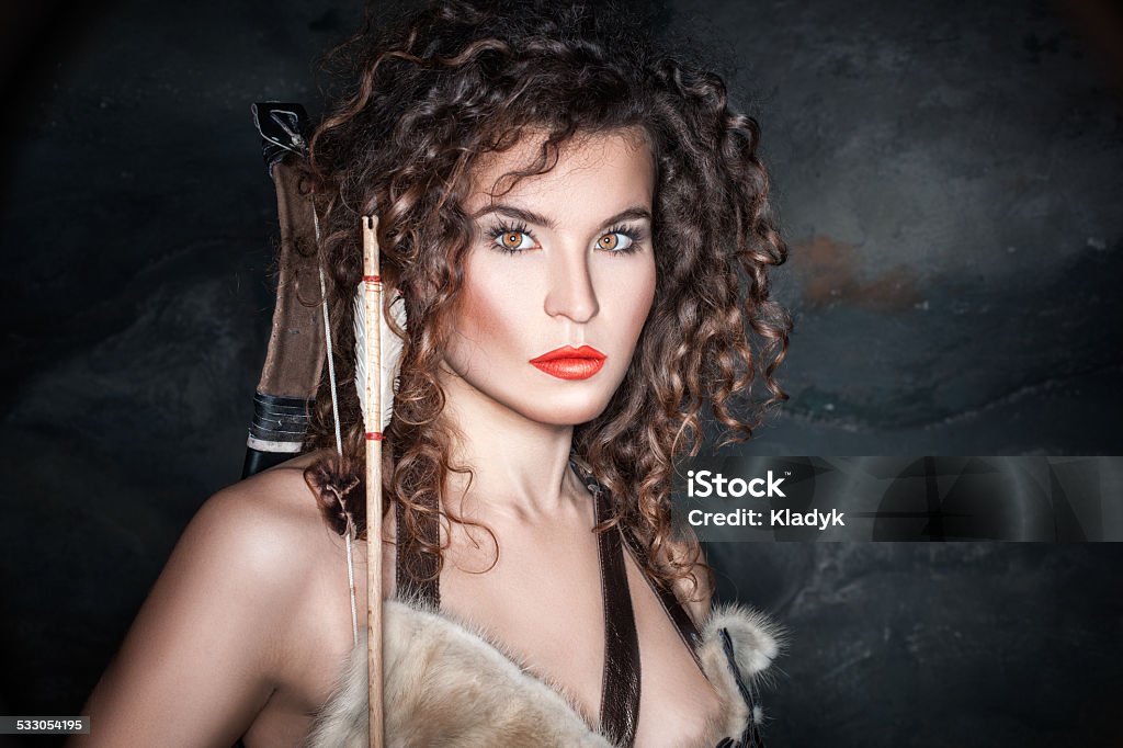 Wild militant girl. Amazon girl with bow and arrow dressed in animal skins. Community Stock Photo