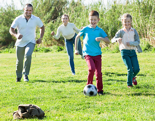 istock Mother and father with two kids  running after  ball 533055014