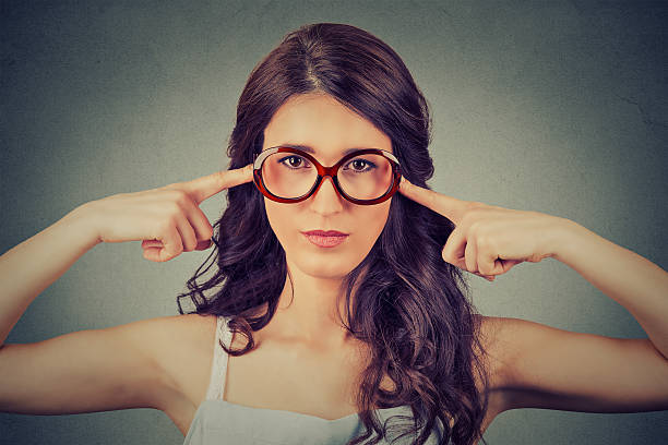 istock Nerdy woman in glasses plugging ears with fingers 533056242