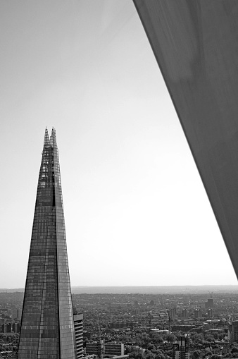 A monochrome view of the Shard in London with a building structure on the right.