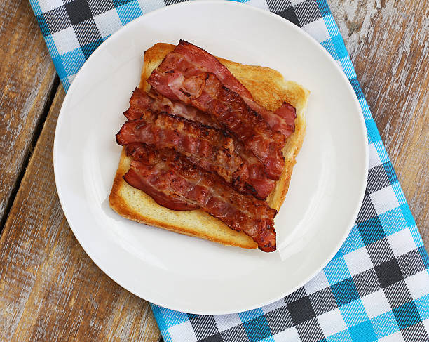 istock Crispy bacon on toast on white plate on checkered cloth 533063974